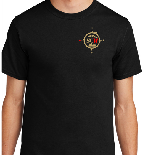 A black short-sleeve crewneck t-shirt with a small circular multicolor graphic printed on the left chest, shown on a cropped model torso against a solid white background.